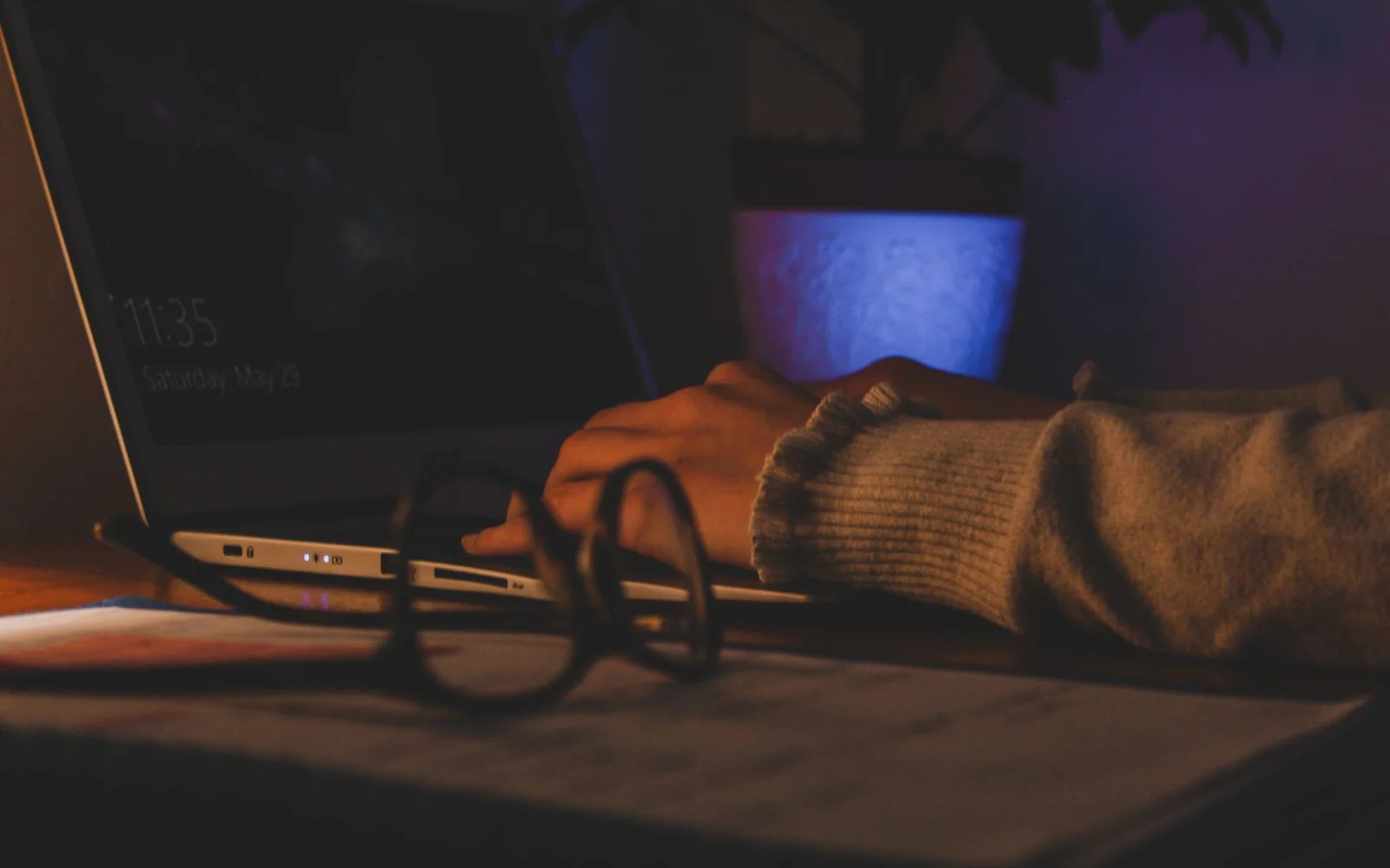 Persoană care lucrează la laptop, cu ochelari pe birou